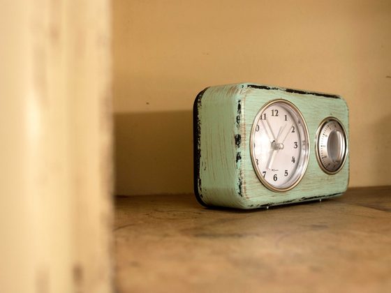 A mint-green enamel mantel clock against an ochre wall.