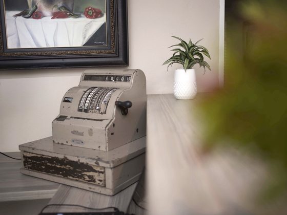 An antique brass and enamel cash register on a side table.