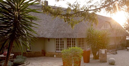 The thatched guest house and its courtyard in late afternoon light.