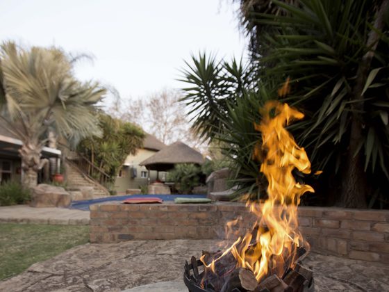 A fire burning in a metal torch beside the pool at dusk.